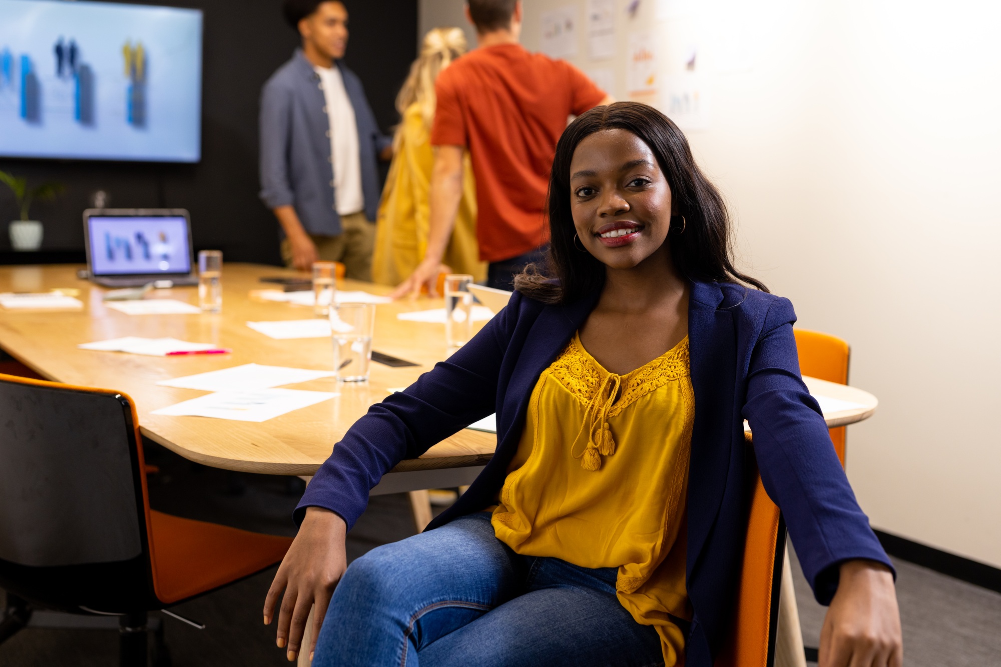 Portrait of happy african american casual businesswoman sitting in meeting room smiling