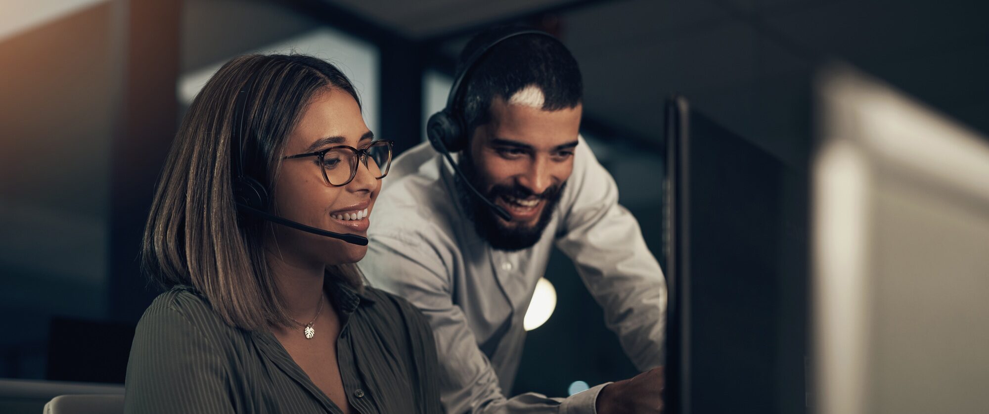 Shot of two call centre agents working together in an office at night